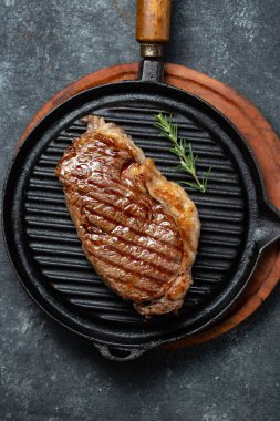 Kaliteli demir ızgara tepsisi ve çatal bıçak setinde kızarmış fileto biftek, siyah arka plan. Üst görünüm