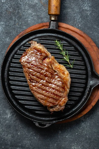 Stekt remsa loin biff på vintage gjutjärn grill pan och bestick set, svart bakgrund. Ovanifrån — Stockfoto