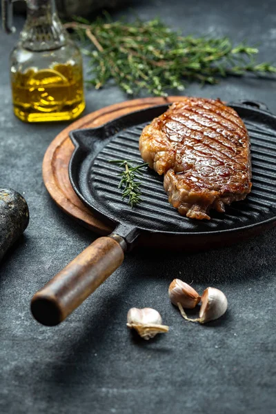 Stekt remsa loin biff på vintage gjutjärn grill pan och bestick set, svart bakgrund. Ovanifrån — Stockfoto