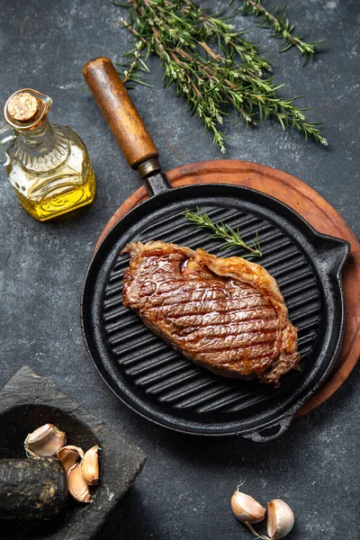 Stekt remsa loin biff på vintage gjutjärn grill pan och bestick set, svart bakgrund. Ovanifrån — Stockfoto