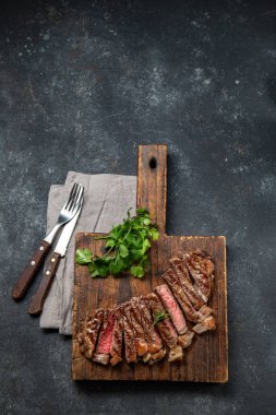 Ahşap tahtada kızarmış fileto biftek, siyah arka plan. Üst görünüm