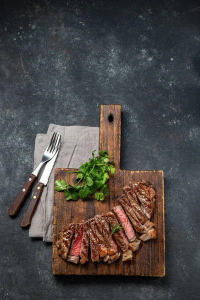 Gebratenes Lendchensteak auf Holzbrett, schwarzer Hintergrund. Ansicht von oben — Stockfoto