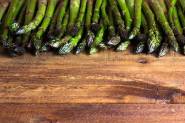 koyu ahşap masa üzerinde taze yeşil kuşkonmaz. arka plan