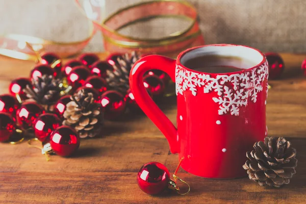 Xícara vermelha de chá e bolas de Natal no fundo de madeira — Fotografia de Stock