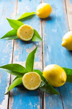 Fresh lemons with leaves on wooden old blue background clipart