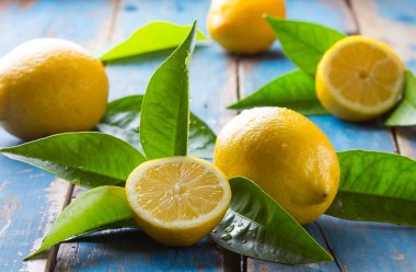 Fresh lemons with leaves on wooden old blue background clipart