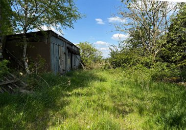 Bir zamanlar yıpranmış bir kulübe yeşil bir tarlada duruyor. Güneş ışığı etraftaki ağaçların arasında sürükleniyor ve Harecroft, Yorkshire, İngiltere 'deki benekli gölgeleri etrafa saçıyor.