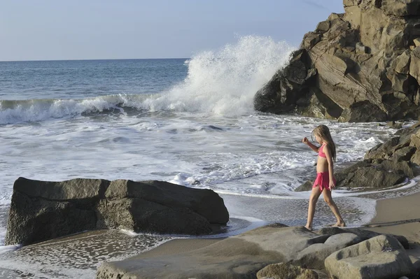 Una chica en traje de baño rosa en la playa rocosa . Imagen de stock