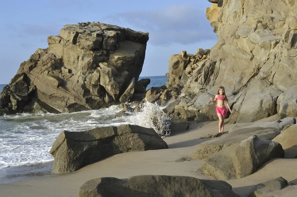 Una chica en traje de baño rosa en la playa rocosa . Imagen de archivo