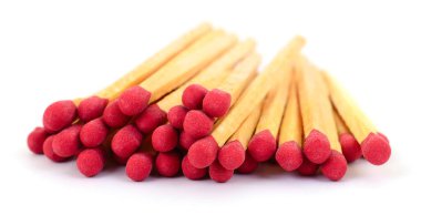 Dağınık ahşap kibrit yığınına yakın çekim, aydınlatılmamış kırmızı kafa, temiz beyaz arka planda izole bir odak etkisi yaratır.