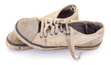 Bir çift yıpranmış, tozlu, yırtık kenarlı, beyaz bir stüdyo arka planında izole edilmiş eski kirli spor ayakkabıları..