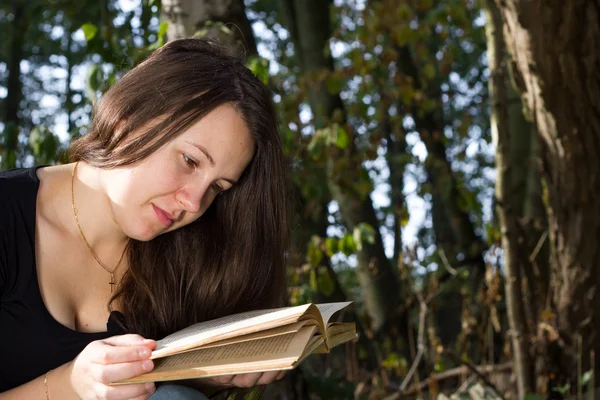 Chica bastante joven leyendo un libro interesante en el enorme bosque — Foto de Stock