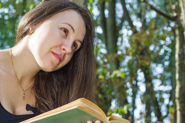 在巨大的森林里读一本有趣的书的漂亮年轻女孩 — 图库照片
