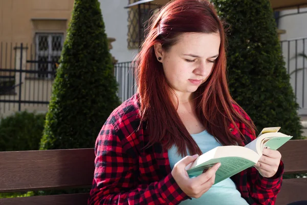 漂亮的年轻女孩在巨大的公园里看书, 坐在 — 图库照片