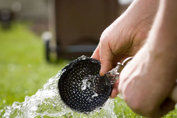 An old hand of active senior washing an equipment of gardening d — Stock Photo, Image