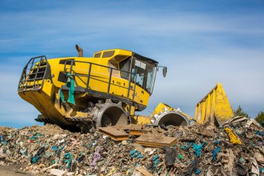 Dev çöp sahasında ya da çöplükte çalışan dev buldozer, kirlilik konsepti