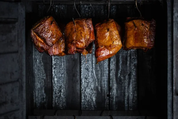 Gros plan d'une viande fumée et du ventre ou de la viande de hêtre avec de la croûte noire dans le fumoir ou le fumeur, concept alimentaire — Photo
