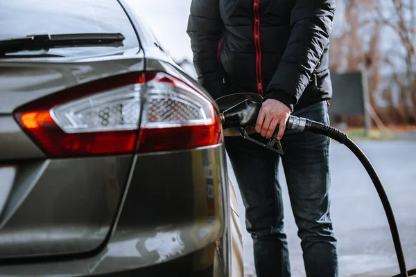 Benzin istasyonunda yakıt ikmali yapan bir adam, arabaya yakıt ikmali yapar.