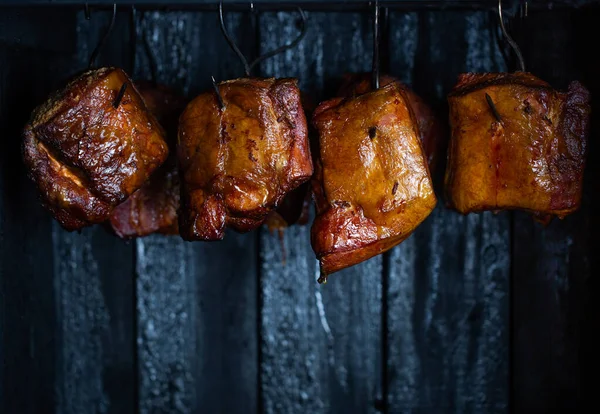 Close up of smoked meat and belly or beech meat with dark crust in the smokehouse or smoker, food concept — Stock Photo, Image