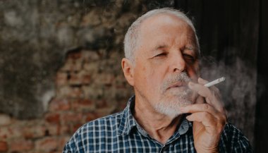 Dışarıda sigara içen yaşlı bir adam, sigara bağımlısı, kötü alışkanlık