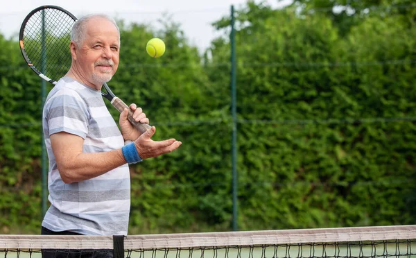 Porträtt av en aktiv senior man på tennisbanan med racket och tennisboll, sport koncept — Stockfoto