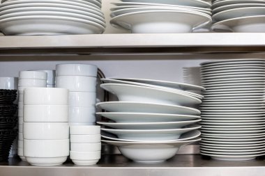 Restorandaki mutfak rafında beyaz tabaklar ve kaseler var.