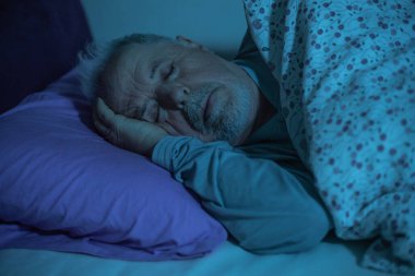 Gece yarısı yatakta uyuyan yaşlı adam, yaşam tarzı konsepti.