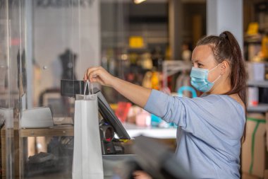 Tezgahtar ya da tezgahtar kız alışveriş merkezindeki alışveriş merkezinin makbuzunu ya da makbuzunu teslim eder, kumaş satışı konsepti