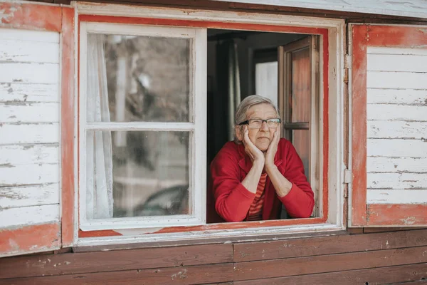 Retrato de mulher ou avó sênior adorável olhando para fora da janela e sorrindo — Fotografia de Stock