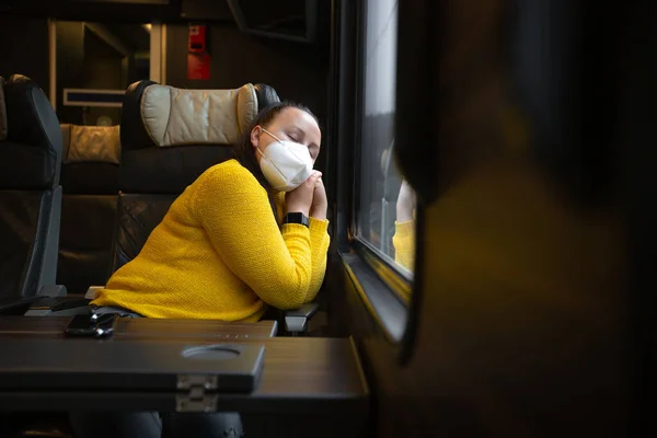 Bonita joven con mascarilla facial también un respirador que viaja en tren durante pandemia covid-19, coronavirus, concepto de transporte — Foto de Stock
