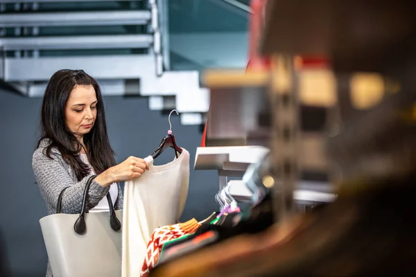 Mujer bastante joven haciendo compras o comprando algo de ropa en la tienda o boutique — Foto de Stock