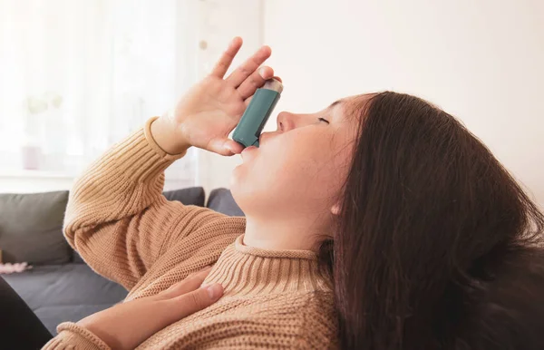 Mujer morena bastante joven usando un inhalador de asma durante un fuerte ataque de asma, producto farmacéutico se utiliza para prevenir y tratar sibilancias y falta de aliento, concepto de salud — Foto de Stock