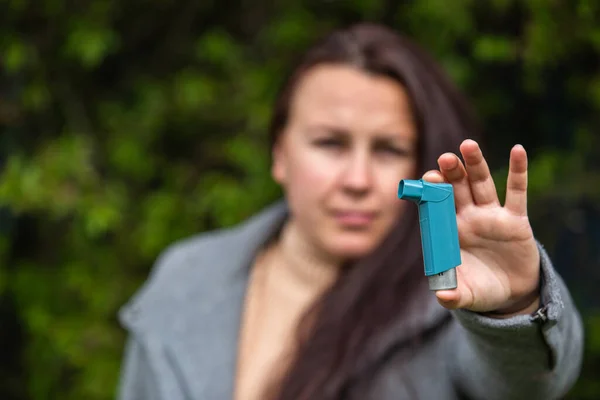 Mujer joven sosteniendo un inhalador de astma contra ataques en sus manos, concepto de salud — Foto de Stock