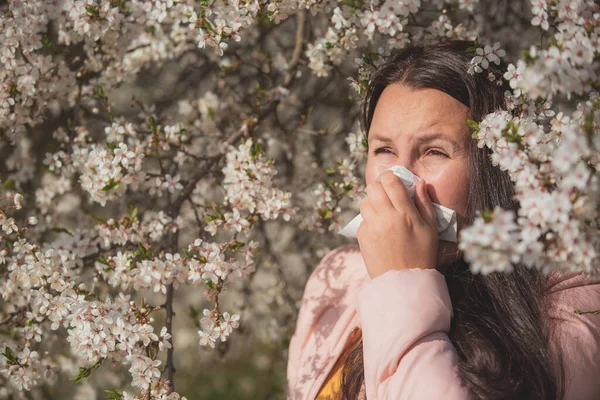 Mujer morena bastante joven con una fuerte reacción alérgica durante la primavera, estornudos con un tejido de papel, concepto de salud — Foto de Stock