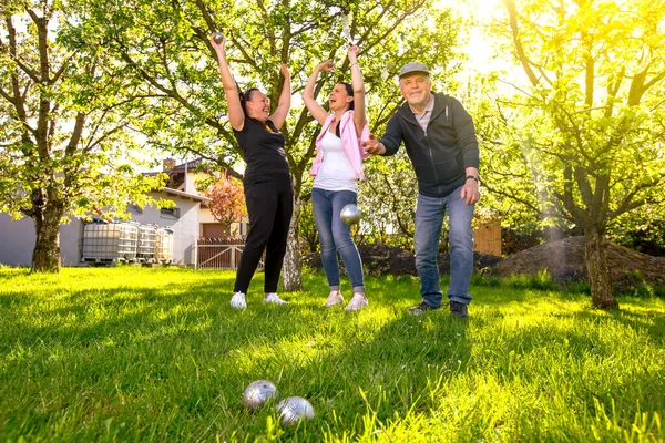 Glad, positive smiling family playing French traditional game petanque in the garden outside during lovely summer day, enjoying leisure time — Stock Photo, Image