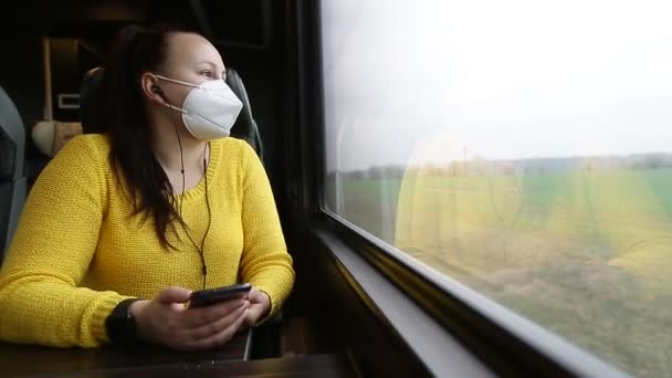 Красивая молодая брюнетка в маске или респираторе, путешествующая на поезде во время пандемии ковид-19, оставайтесь в безопасности — стоковое видео