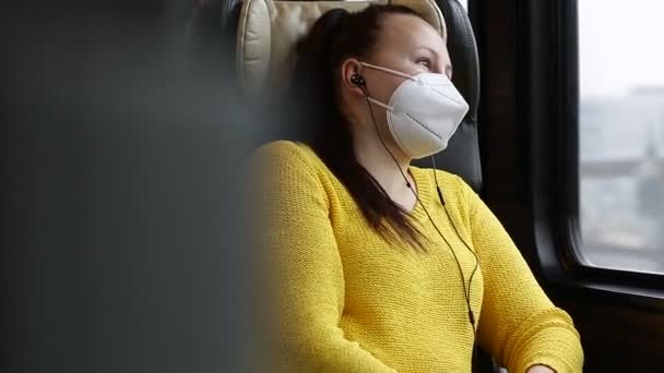 Mujer morena bastante joven con mascarilla facial o respirador viajando en el tren durante la pandemia de covid-19, mantenerse a salvo viajar — Vídeos de Stock