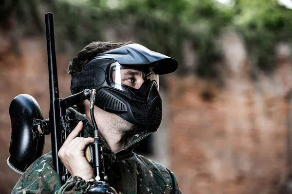 Porträtt av ung man med skyddsmask, paintball pistol och kamouflage slitage, redo för en åtgärd paintball spel — Stockfoto
