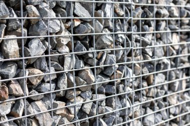 Metal bir ağ arkasında küçük granit taşlar, çit tasarımı, bahçe konsepti