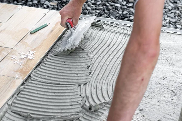 Le mani del piastrellista sdraiato o l'installazione moderna, piastrelle di ceramica sopra il cemento sulla terrazza del giardino, pavimento di piastrelle, concetto di costruzione — Foto Stock