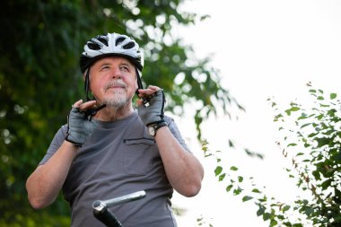 Gülümseyen, bisiklete binen ya da dışarıda bisiklete binen, ormanda bisiklet sürmeden önce koruyucu kaskını takan, sağlıklı yaşam tarzı spor anlayışı