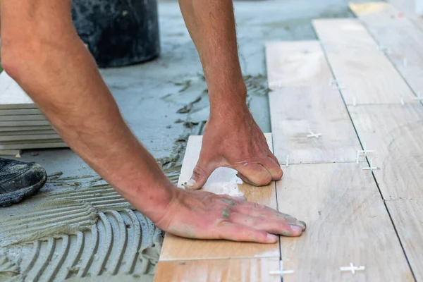 Руки професійного плитки лежать або встановлюють сучасну керамічну плитку над цементом на садовій терасі, плиткою підлоги, будівлею і концепцією тротуарної плитки — стокове фото
