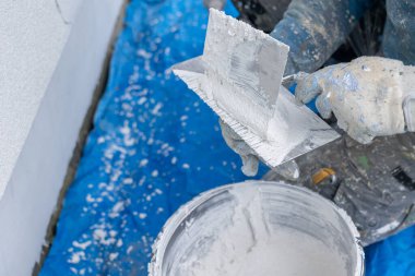 Kovanın üzerinde taze alçı karışımı olan malayı tutan bir işçi.