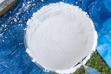 Bir kovada beyaz alçı tozu ve su karışımı ev yenileme malzemesi hazırlıyorum.