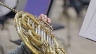 Orkestra provası sırasında bando kornosu çalan bir müzisyenin yakın çekimi.