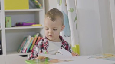 Masada makasla kağıt kesen sevimli çocuk evde motor becerilerini geliştiriyor.