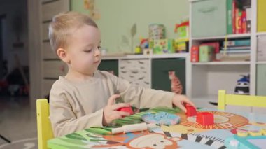 Odasındaki masada renkli oyun hamuruyla yaratıcı aktivitelerden hoşlanan sevimli küçük çocuk.