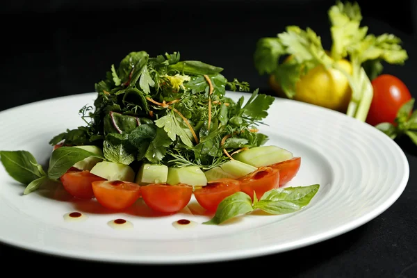 Салат в тарелке на черном фоне — стоковое фото