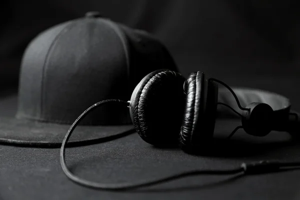 Black headphone with hat on black background — Stock Photo, Image