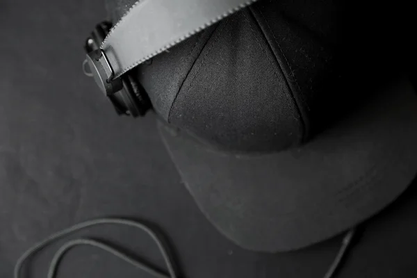 Svarta hörlurar med hatt på svart bakgrund — Stockfoto